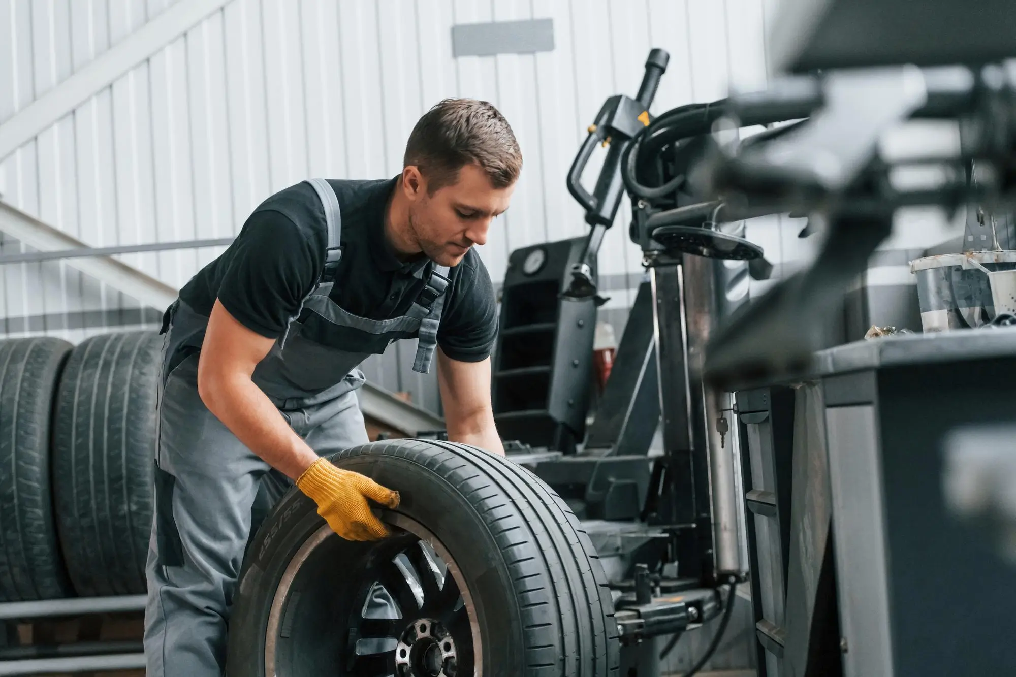Mechanik w serwisie wulkanizacyjnym podczas wymiany opon letnich na feldze aluminiowej.